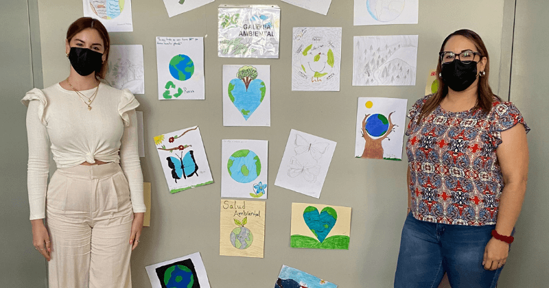 Staff standing with drawings done by students
